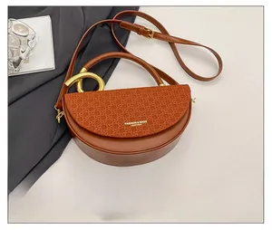 Close-up of brown leather saddle bag featuring woven texture and gold metal handle