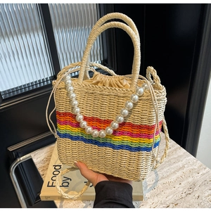 Detail of a rainbow striped straw bucket bag with elegant pearl handles and drawstring closure