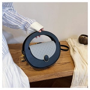 Detail of round black shoulder bag with grey woven lid on wooden bench background