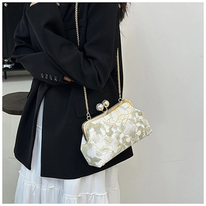 Détail d'un sac de soirée brodé à fleurs avec fermoir perle et bandoulière dorée