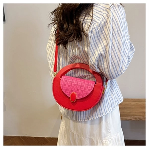 Detail of red circular crossbody bag with pink woven flap and metal oval buckle on model