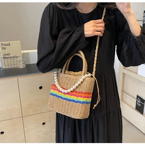 Macro detail of hand-woven straw bucket bag with rainbow stripes and pearl handle