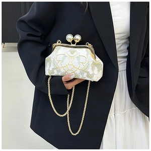 Gros plan détaillé de la broderie florale sur sac crème vintage avec fermoir perles