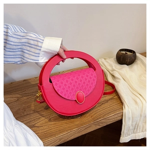 Detail of fuchsia crossbody bag with woven texture flap and round top handle on wooden bench