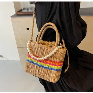 Detailed shot of a woven rainbow straw bag with pearl handle and canvas drawstring