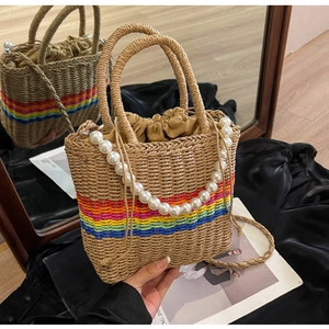 Detail of woven beach bag with rainbow stripes, large pearls, and drawstring liner