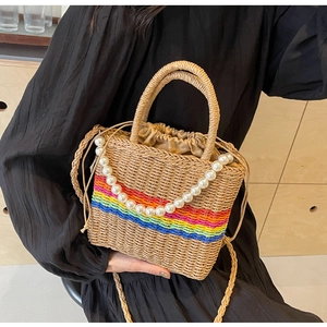 Detail of woven straw beach bag with rainbow stripes, drawstring and pearl handle
