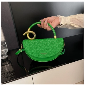 Close-up of green saddle bag showing woven texture and gold metal knot handle detail