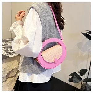 Detail view of round pink crossbody bag featuring woven texture flap and golden hardware