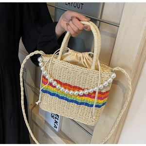 Detail of hand-woven straw bag with colorful rainbow stripes and pearl strap embellishment