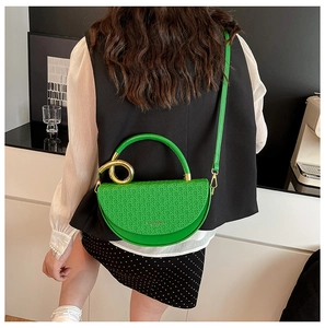 Detail of bright green woven texture semi-circle bag with golden knot metal ring