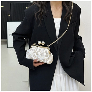 Détail d'un sac brodé vintage avec motifs floraux, fermoir perle et bandoulière dorée