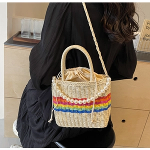 Detailed shot of rainbow striped woven bucket bag with pearl handle and drawstring liner