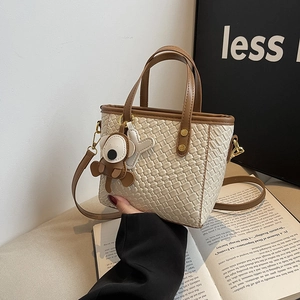 Sac seau tissé crème avec garniture marron et breloque ours, style bandoulière chic