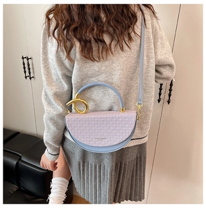 Detail view of the elegant lavender woven saddle bag with gold metal ring handle attachments