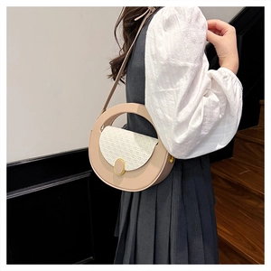 Fashionable round shoulder bag in beige with textured flap shown on a model