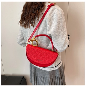 Detail of red saddle bag with woven texture, gold metal handle and fashion branding