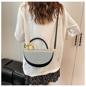 Rear view of a model wearing the bicolored woven saddle bag with gold ring and black straps
