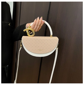 Detail of saddle bag with beige woven texture, white leather, and spiral gold metal handle