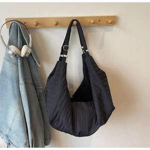 Detail of black quilted shoulder bag featuring pleated fabric and moon-shaped design