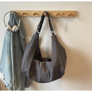 Detail of dark grey pleated hobo bag with adjustable strap and matte fabric texture