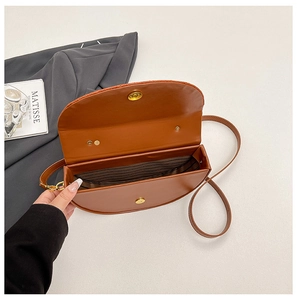 Detailed view of the brown saddle bag interior with striped lining and magnetic buckle
