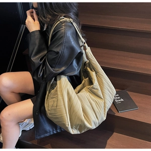 Macro shot of large khaki pleated crossbody bag showing soft nylon texture and volume