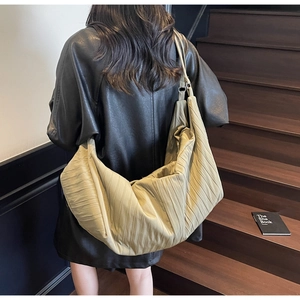 Close-up of khaki pleated shoulder bag showing the vertical texture and soft fabric