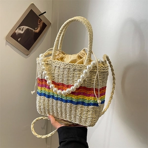 Handmade woven straw bag with rainbow stripes, pearl handle and drawstring closure