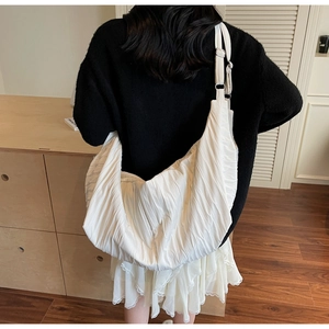 Detail of white pleated hobo bag showing large capacity and silky texture on model