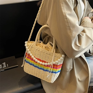Chic woven beach bag with rainbow stripes and pearl strap accessory on beige straw