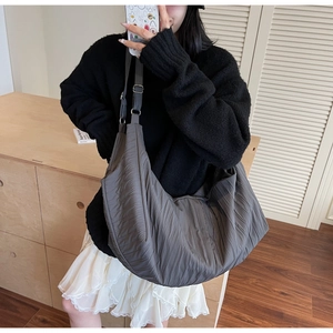 Detail of grey dumpling bag showing pleated texture and adjustable shoulder strap