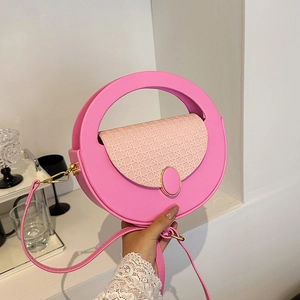 Pink circular crossbody handbag with woven texture and creative cutout handle design