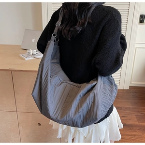 Detail of adjustable wide shoulder strap with metal ring on dark grey ruched bag