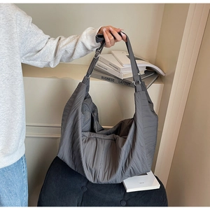 Detail of grey pleated large capacity hobo bag featuring soft texture and adjustable strap