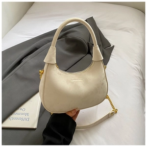 Detail of cream velvet half-moon bag featuring gold chain strap and soft suede texture