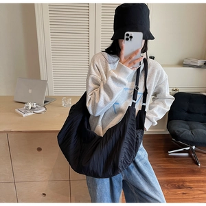 Mirror selfie showing large black pleated crescent bag with adjustable wide strap