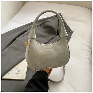 Close-up of light grey velvet crescent bag with gold hardware and chain detail