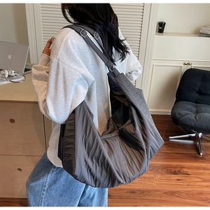 Detail of adjustable silver buckle on large dark grey quilted crossbody tote bag