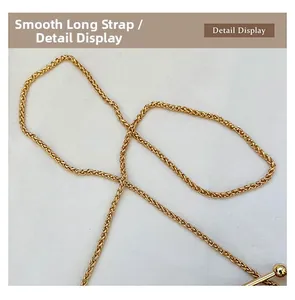 Detail of a smooth golden chain strap with woven metal texture and spherical metal end