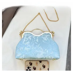 Close-up of light blue floral embroidery satin bag with gold metal handle and chain
