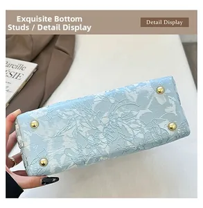 Detail of light blue floral fabric bag bottom with four protective gold metal feet