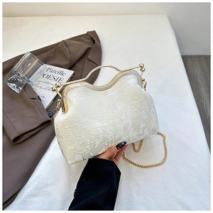 Detail of cream shell bag featuring floral embroidery and golden metal handle