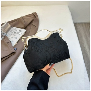 Detail of vintage black embroidered shell bag with gold handle and chain on a brown suit