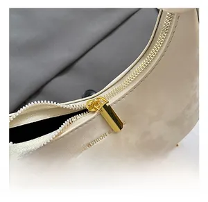 Detail view of smooth golden metal zipper and chain on an off-white velvet crescent bag