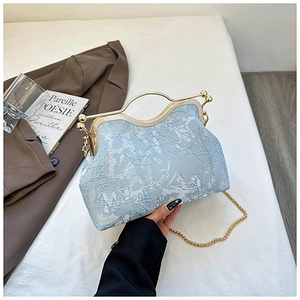 Macro view of light blue shell bag with floral embroidery and gold metal clasp frame