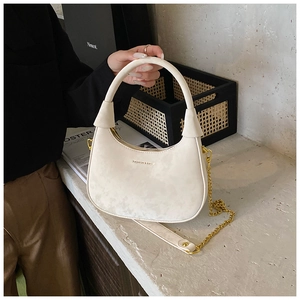 Detail of cream velvet crescent bag with gold chain strap and metal logo lettering