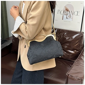 Detail of elegant black shell bag with floral embossing and gold chain strap