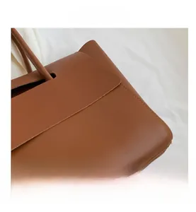 Close-up of fine stitching and smooth matte leather texture on brown tote bag detail