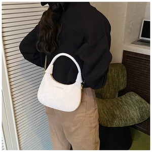 Chic white velvet crescent bag with gold chain strap shown in a stylish indoor setting